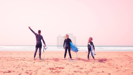 Photo for Father and son surfers with board at sunset - Royalty Free Image