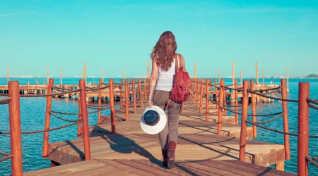 Photo for Woman walking on wooden pier looking at the sea - Royalty Free Image