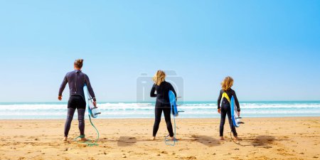 Téléchargez les photos : Famille, fether et fils avec planche de surf sur la plage - en image libre de droit