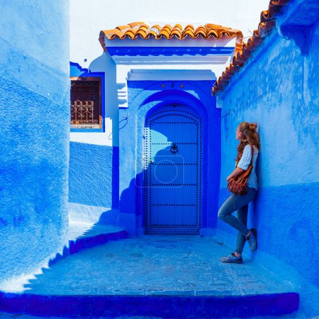 Téléchargez les photos : Tourisme au Maroc-Femme touriste dans belle rue bleue à Chefchaouen - en image libre de droit