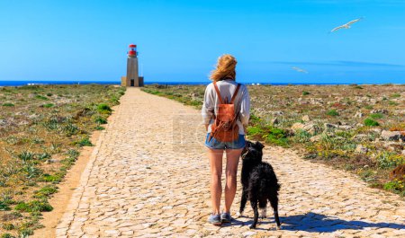 Foto de Mujer y collie fronterizo viajan en Sagres- turismo en Portugal- Farol de Sagres - Imagen libre de derechos