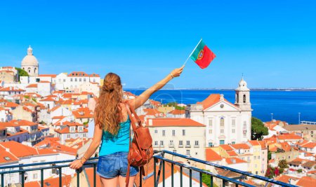 Foto de Mujer con los brazos levantados sosteniendo la bandera portuguesa mirando al mirador de Lisboa - Imagen libre de derechos