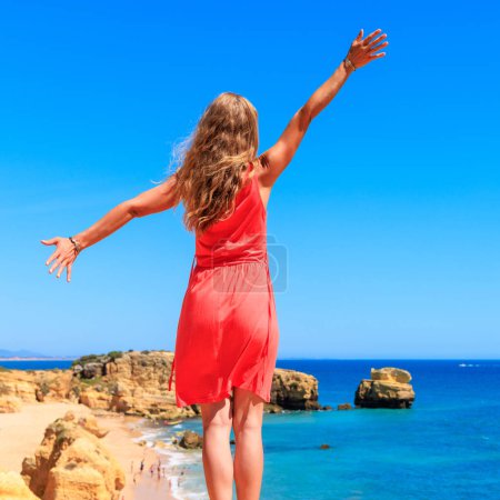 Photo for Woman in red dress enjoying Atlantic ocean panoramic view - Algarve in Portugal - Royalty Free Image