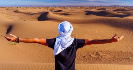 Téléchargez les photos : Homme les bras tendus dans le désert- Sahara au Maroc - en image libre de droit