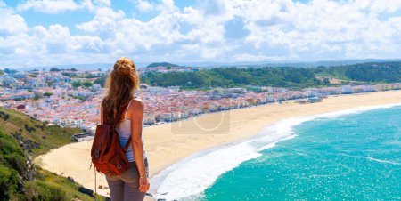Foto de Turista mujer mirando a la vista panorámica de la famosa playa de Nazare en Portugal, Leiria - Imagen libre de derechos