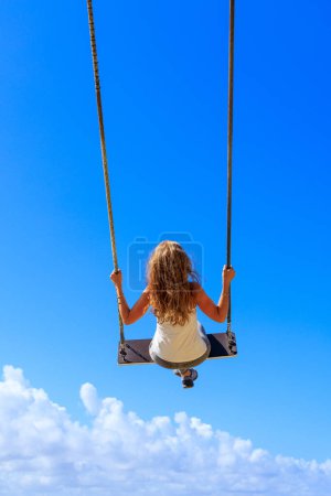 Téléchargez les photos : Femme sur swing sur bleu ciel - en image libre de droit