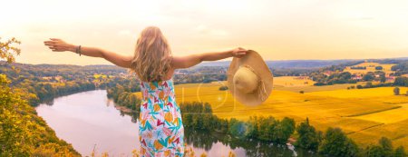 Foto de Mujer joven turista con vestido mirando a la vista panorámica del campo en Francia- Dordogne - Imagen libre de derechos