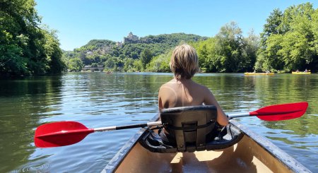 Téléchargez les photos : Adolescent pagayant dans la rivière française sur canoe- Dordogne - en image libre de droit