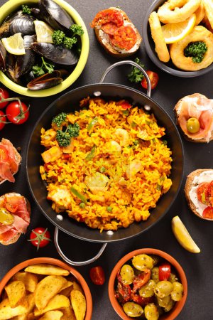Téléchargez les photos : Assortiment de plats espagnols Paella plateaux de fruits de mer, moules, rondelles d'oignons frits, patatas bravas, olives - en image libre de droit