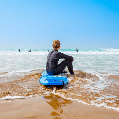 Téléchargez les photos : Adolescent assis sur surf regardant océan - en image libre de droit