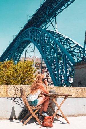 Téléchargez les photos : Femme touriste au téléphone portable et regardant pont de fer à Porto, capitale du Portugal - en image libre de droit