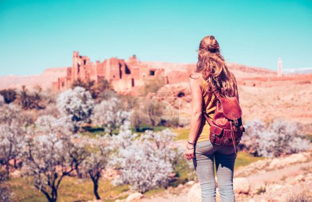 Téléchargez les photos : Femme touriste regardant la ville fortifiée, Telouet Kasbah au Maroc au printemps - en image libre de droit