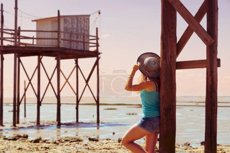 Téléchargez les photos : Tour tourisme en France, Charente Maritime, Gironde- Touriste femme jouissant d'un tapis traditionnel, cabane de pêche sur la côte atlantique de l'océan - en image libre de droit