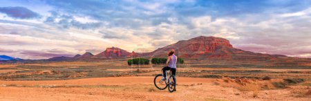 Téléchargez les photos : Femme à vélo bénéficiant d'une vue panoramique sur la campagne et la montagne (Aragon, Espagne) - en image libre de droit