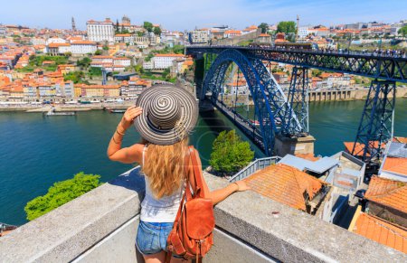 Foto de Oporto destino de viaje- Mujer disfrutando de vista panorámica del paisaje de la ciudad, famoso puente y el río Duero de Oporto- Portugal - Imagen libre de derechos