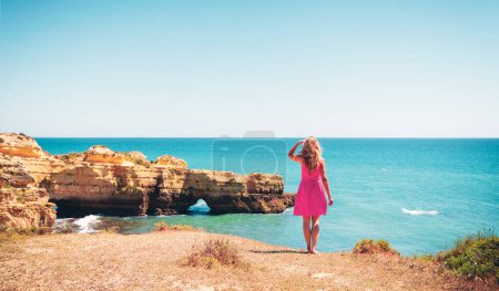 Foto de Mujer con vestido rojo mirando el hermoso mar- Portugal, Algarve - Imagen libre de derechos
