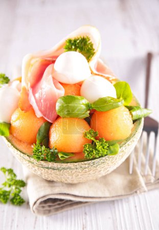 Téléchargez les photos : Salade de melon au jambon de prosciutto, mozzarella et basilic - en image libre de droit