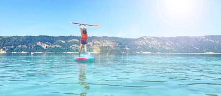 Téléchargez les photos : Enfant debout pagaie dans le lac- sport, aventure, concept de voyage en famille - en image libre de droit