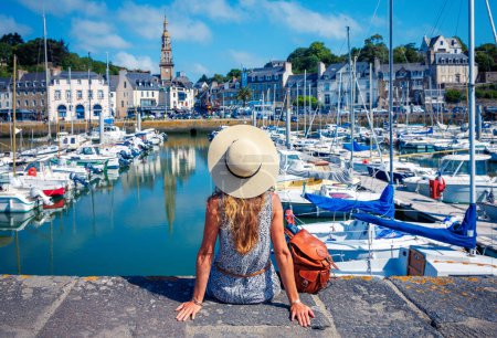 Téléchargez les photos : Vue arrière d'une femme avec chapeau regardant le village français- voyage, vacances, concept touristique (Bretagne en France, Saint Brieuc) - en image libre de droit