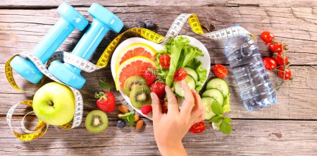 Foto de Alimentación saludable, ensalada de frutas y verduras con accesorios deportivos- fitness, concepto activo y de pérdida de peso - Imagen libre de derechos