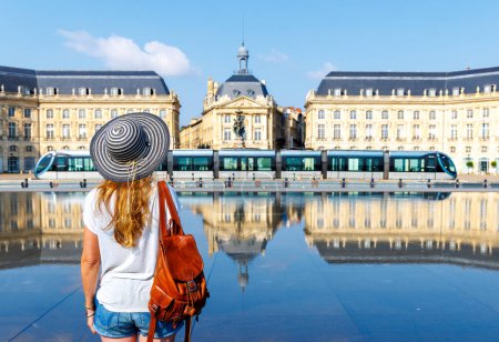 Téléchargez les photos : Vue arrière d'une femme regardant un miroir d'eau sur la place de la Bourse à Bordeaux- France - en image libre de droit
