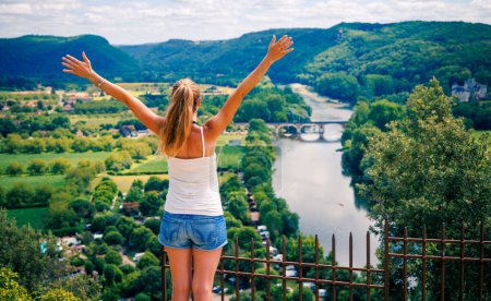 Téléchargez les photos : Femme heureuse à bras ouverts bénéficiant d'une vue panoramique sur le paysage et la rivière Dordogne- France - en image libre de droit