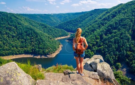 Téléchargez les photos : Femme randonnée rocher bénéficiant d'une vue panoramique sur la rivière et la forêt (Dordogne en France) - Aventure, réussite, concept de femme active - en image libre de droit