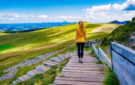 Téléchargez les photos : Femme avec des vêtements de sport marchant sur un sentier en bois en montagne- Auvergne en France - en image libre de droit