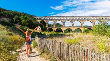 Foto de Mujer turista disfrutando del acueducto romano Pont du Gar- Famoso sitio turístico en Francia- Gard, Occitanie - Imagen libre de derechos