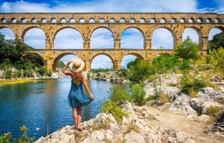 Téléchargez les photos : Touriste femme avec robe et chapeau profitant du Pont du Gard en France - en image libre de droit