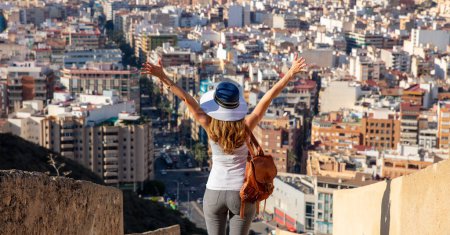 Téléchargez les photos : Heureuse femme touristique profitant d'une vue panoramique sur Alicante ville skyline- tourisme, concept de voyage - en image libre de droit