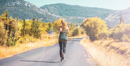 Foto de Mujer disfruta corriendo afuera al amanecer en la carretera en el país, deporte, concepto de mujer activa - Imagen libre de derechos