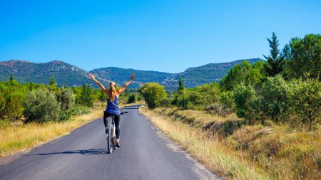 Foto de Mujer feliz con los brazos abiertos en bicicleta en la carretera- Francia- viajes, deporte, concepto de mujer activa - Imagen libre de derechos