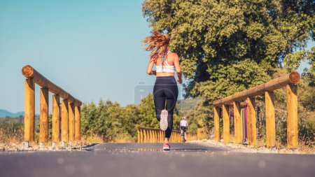 Foto de Deportiva mujer corriendo y hombre en bicicleta en la carretera en la naturaleza - Imagen libre de derechos