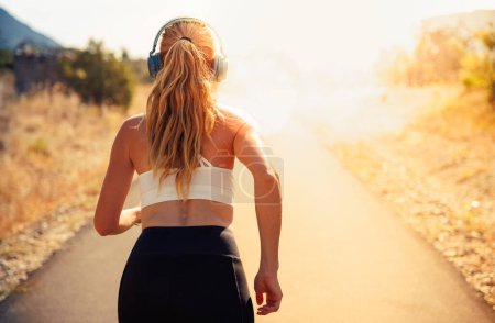 Photo for Woman running in the morning with earphones music motivation - Royalty Free Image