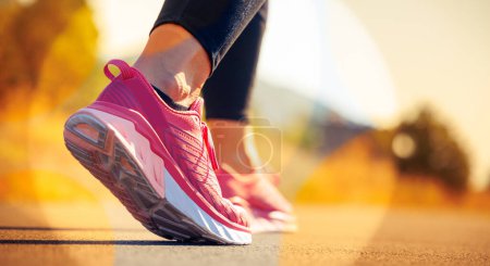 Téléchargez les photos : Close up on runner foot shoe on sunrise asphalt road sport, running, jogging, fitness concept - en image libre de droit