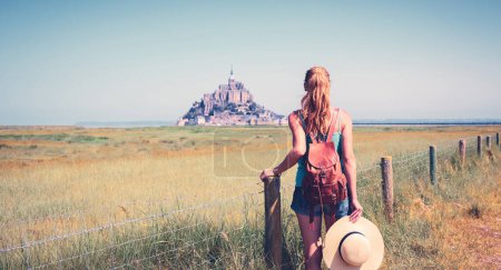 Téléchargez les photos : Vue arrière d'une femme regardant Le Mont Saint Michel- Normandie en France - en image libre de droit