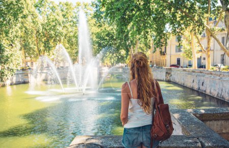 Téléchargez les photos : Nîmes ville en France, Voyageur ou étudiant regardant fontaine - en image libre de droit