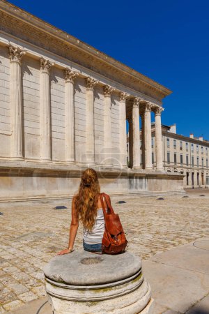 Téléchargez les photos : Nîmes ville en France, Voyageur ou étudiant assis sur la place de la maison carre. - en image libre de droit