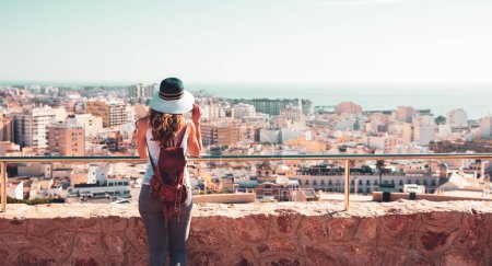 Téléchargez les photos : Femme avec chapeau regardant la vue panoramique de la ville espagnole skyline Almeria en Espagne - en image libre de droit