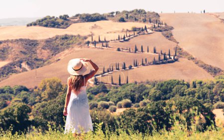 Téléchargez les photos : Attrayant jeune femme avec chapeau et robe blanche voyageant dans le paysage toscan Italie - en image libre de droit