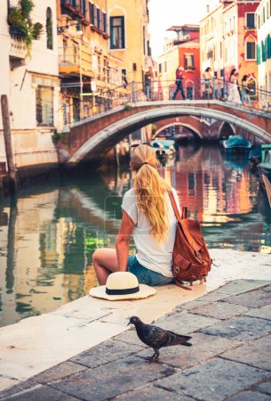 Téléchargez les photos : Touriste féminine assise sur le sol regardant le pont traditionnel et la télécabine dans la ville de Venise Voyage, tourisme, vacances en Italie, Europe - en image libre de droit