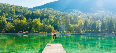 Photo for Happy woman jumping on pier, breathtaking landscape with emerald lake in mountain- Slovenia- freedom,travel,tourism,healthy lifestyle concept - Royalty Free Image