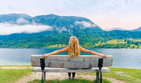 Foto de Mujer sentada en el banco mirando al lago- relajarse, vacaciones, concepto de gente serena - Imagen libre de derechos