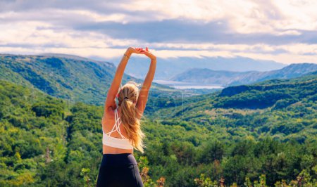 Photo for Fit, sporty woman stretching outside enjoying beautiful landscape view- outdoor fitness, active lifestyle, wellness concept - Royalty Free Image