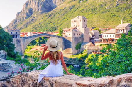 Téléchargez les photos : Touriste femme en robe blanche et chapeau profitant de la vieille vue sur le pont à Mostar- Bosnie - en image libre de droit
