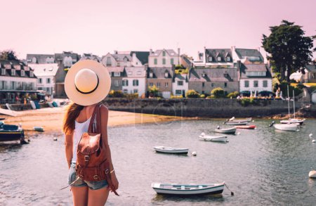 Foto de Vista trasera de la mujer disfrutando de la hermosa playa y barcos, Bretaña en Francia- turismo turístico, viajes, vacaciones - Imagen libre de derechos