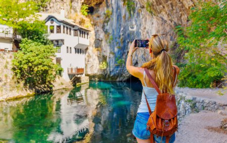 Foto de Mujer turista tomando fotografías en Bosnia y Herzegovina- Casa Blagaj, cueva y río - Imagen libre de derechos