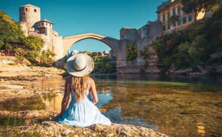 Téléchargez les photos : Femme en robe blanche regardant Old bridge dans la ville de Mostar- Bosnie Herzégovine - en image libre de droit
