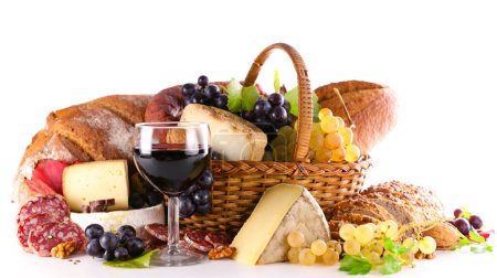 Photo for Wicker basket with bread, salami, cheese and grapes- Red wine glass isolated on white background - Royalty Free Image